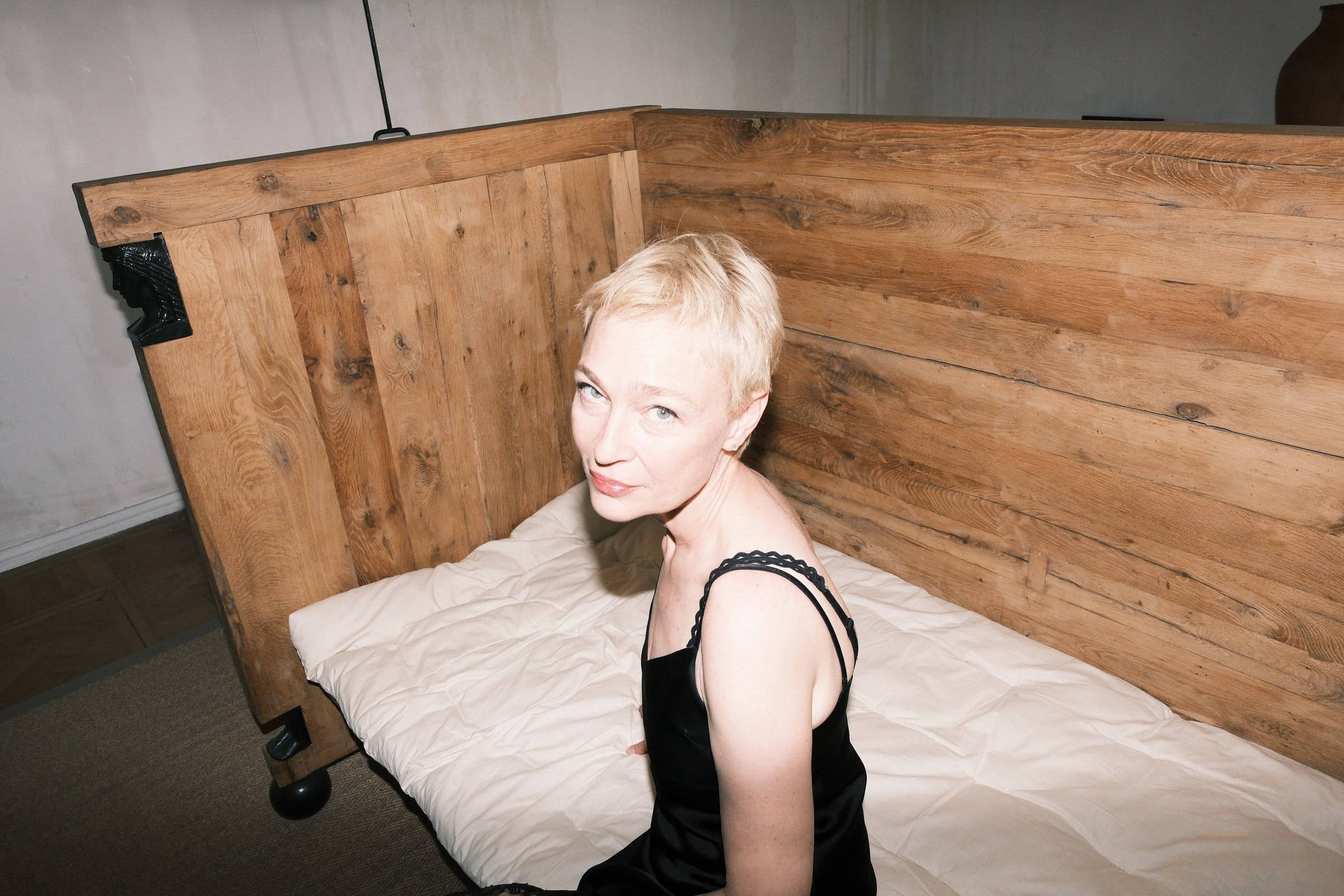 A performer sitting on a mattress inside a wooden box